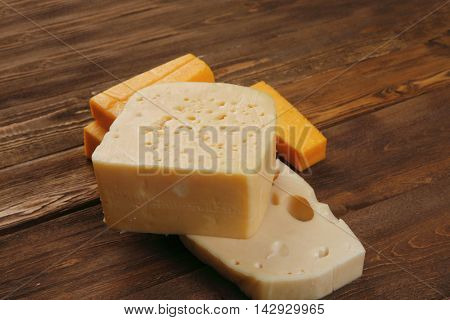 various types of fresh raw aged delicatessen cheese on wooden table cheddar edam swiss