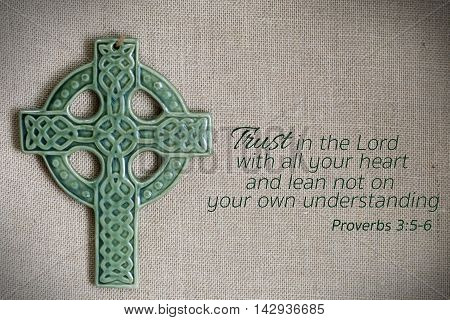 green cross and proverb bible passage on burlap background
