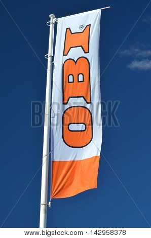 CIRCA AUGUST 2016 - GDANSK: sign of OBI on waving flag against blue sky. OBI is the largest do it yourself retailer in Europe. It was founded in 1970 in Hamburg, Germany.