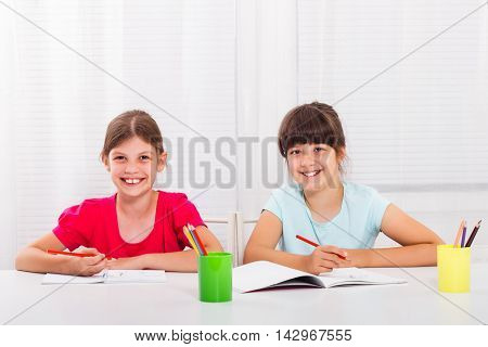 Cute little girls are enjoy drawing and writing together.