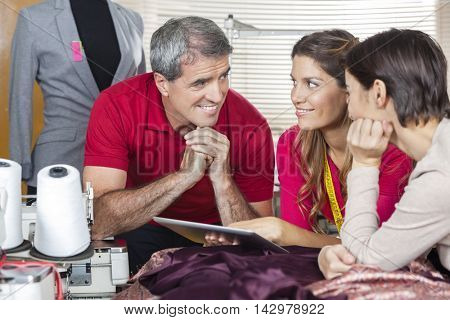 Tailors Using Tablet Computer While Leaning On Workbench