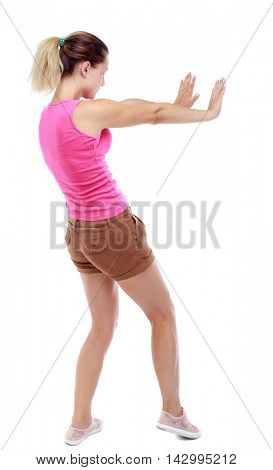 back view of woman pushes wall.  Isolated over white background. Rear view people collection. backside view of person. Sport blond in brown shorts pushes away someone.
