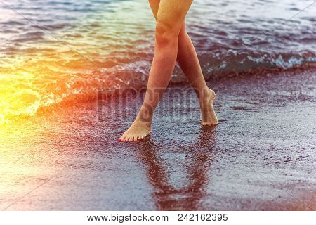 A Girl Walks Along The Seashore At Sunset Time