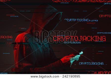 Cryptojacking Scam Concept With Faceless Hooded Male Person Using Tablet Computer, Low Key Red And B