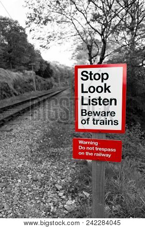 Railway Warning Sign In Black And White With Red Signpost Reading 