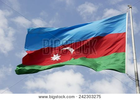 Flag Of The Country Azerbaijan Developing In The Wind Against The Blue Sky