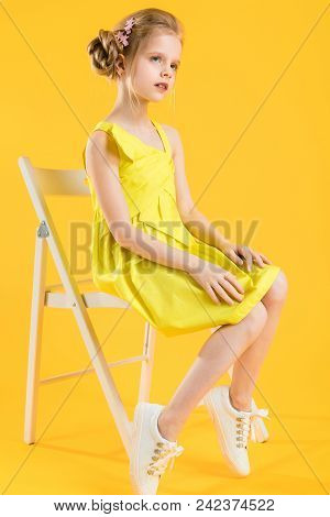 Portrait Of A Teenage Girl In A Yellow Dress. At The Child Hair Are Collected In A Fascicle And Are 