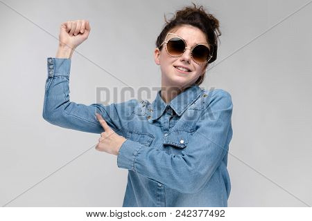 Young Girl In Black Cat Glasses On A Gray Background. Portrait Of A Young Beautiful Girl. Charming G