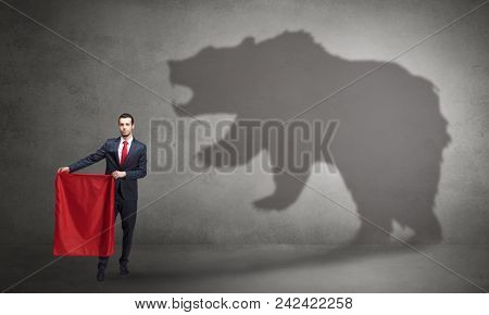 Businessman standing with red cloth in his hand and big bear shadow on his background