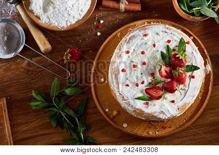 Strawberry Tart Covered With Whipped Sour Cream Surrounded By Organic Ingredients Over Wooden Backgr