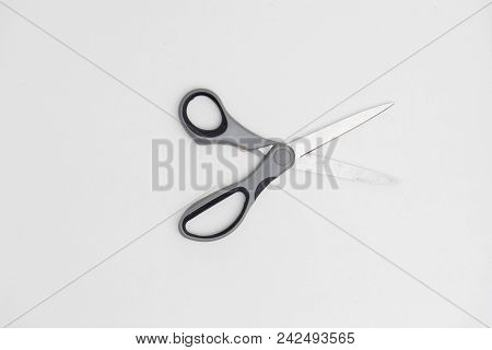 Opened Scissors With Red Helve Against A White Background