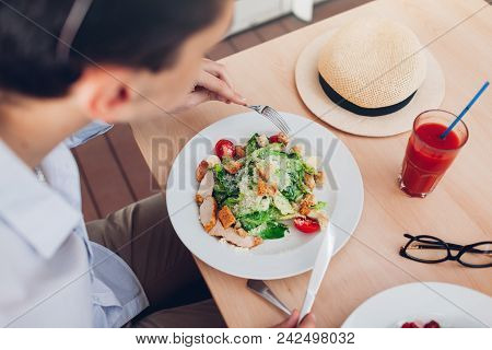 Man Eating Caesar Salad And Drinking Tomato Juice In Restaurant. Traveller Having Lunch In Cafe.
