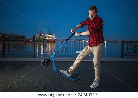 Young Handsome Guy Posing With Kick Scooter By Night Street Background.