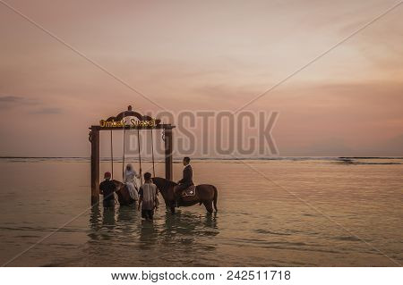 Indonesian Wedding Couples Riding In The Sea At Sunset  In Front Of A Swing, The Bride Wears A White