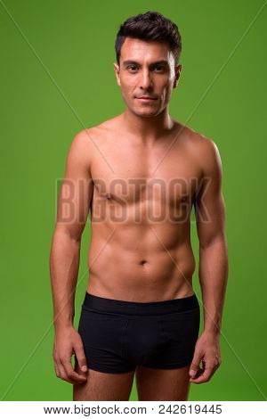 Studio Shot Of Young Handsome Hispanic Man Shirtless Against Chroma Key With Green Background