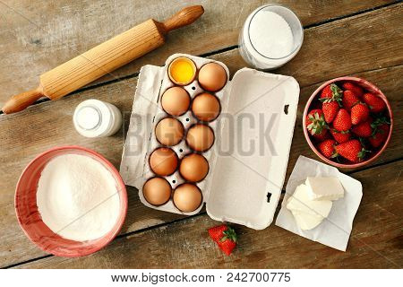 Set Raw Ingredients For Cooking Strawberry Pie Or Cake On Wooden Background. Eggs, Flour, Milk, Suga