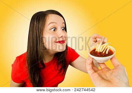 Young Woman Eats Fries With Ketchup. Isolated On Yellow Background.