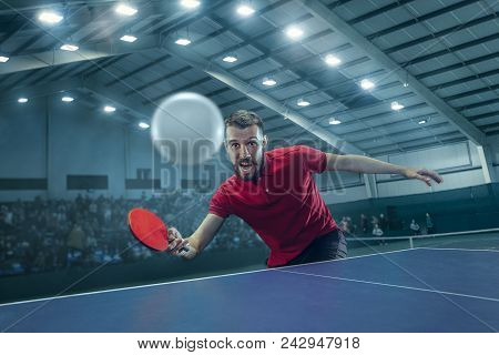 The Table Tennis Player In Motion. Fit Young Sports Man Tennis-player In Play On Sport Arena Backgro
