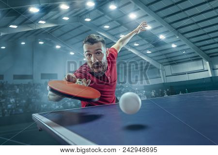 The Table Tennis Player In Motion. Fit Young Sports Man Tennis-player In Play On Sport Arena Backgro