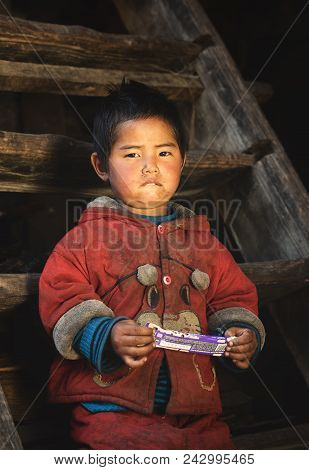 Prok Village / Nepal - October 14 2017. Sweet Little Boy Indoors With Chocolate Candy. Nepalese Cute