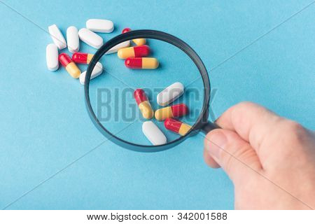 Concept - Pharmaceutical Testing, Testing Of Medicines, Magnifying Glass, Tablets On A Blue Backgrou