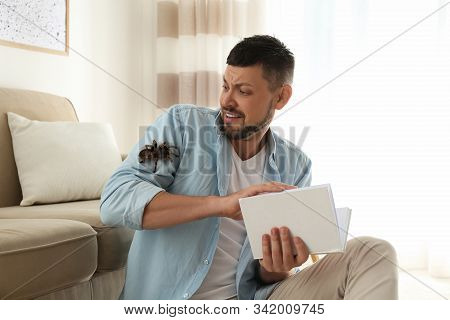 Scared Man With Tarantula At Home. Arachnophobia (fear Of Spiders)