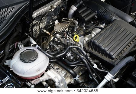 The Engine Compartment And Engine Of A Modern Car. In The Center Of The Frame Are Gears And Timing B