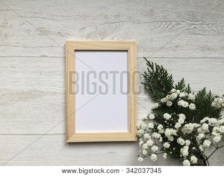 A Still Life Flat Lay Concept On The Light Wooden Background, A Blank Photo Frame, Gypsophila Little