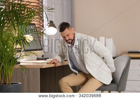 Man Suffering From Hemorrhoid At Workplace In Office