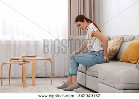 Young Woman Suffering From Hemorrhoid On Sofa At Home