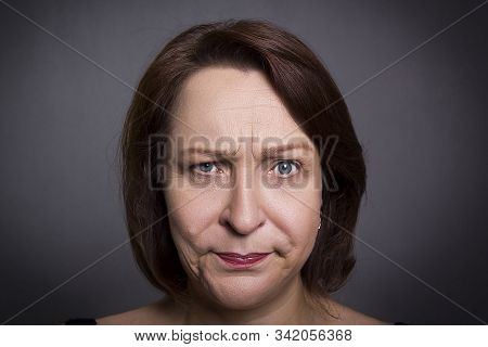 Woman Grimaces In Front Of Camera On Black Background