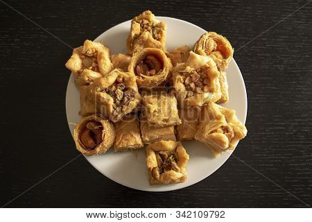 Traditional Eastern Assorted Baklava. Top View. Arabic Baked Sweets In White Plate On Dark Wooden  T