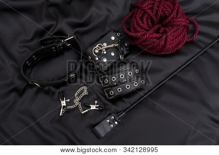 Leather Handcuffs, Shibari Rope, Nipple Clamps, Chain Collar And Stack On Black Background. Accessor