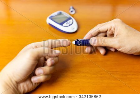 Man Using Lancelet On Finger Checking Blood Sugar Level.