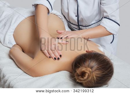 Masseur Makes A Relaxing Massage On The Neck, Shoulders, Back And Collarbones Of A Young Beautiful W