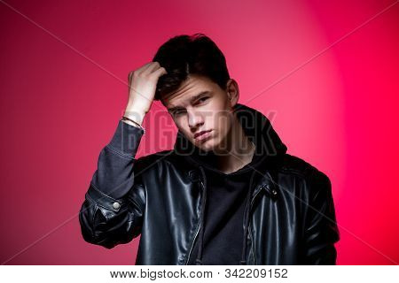 Cute Brutal Man In Black Leather Jacket Model Style. Portrait Of A Handsome Guy On Pink Studio Backg