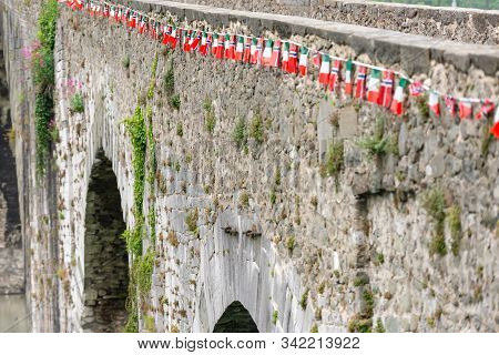 Bridge Of A Devil. Bridge Over The River In Tuscany. Built In The 11 Century. Flags On Humpback Brid