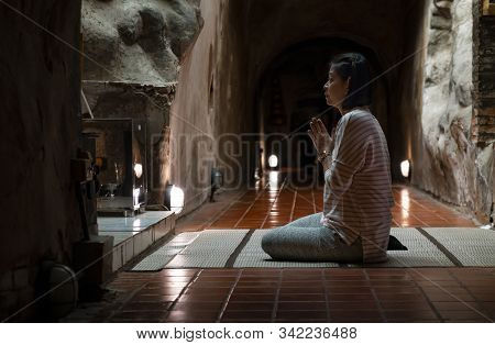 Asian Tourist Woman Praying To Old Buddha At Wat Umong Or Umong Temple Of Chiang Mai, Thailand. In T