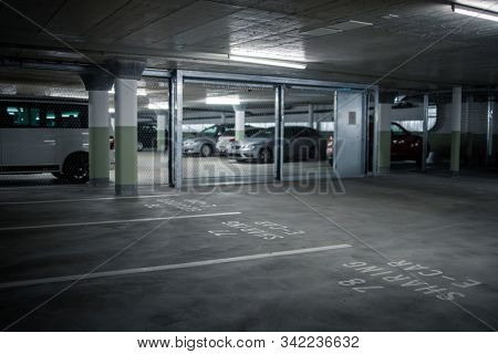 Gated underground parking. Cars parked in a garage with no people. Many cars in parking garage interior. Underground parking with cars (color toned image)