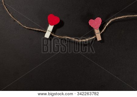 Two Red Hearts On A Clothespin On A Black Background. View From Above. Valentines Day Concept.