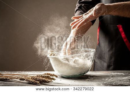 A Cook In Black Knead The Dough In A Glass Bowll Bowl For Cooking Bread In The Kitchen. Yeast Dough 