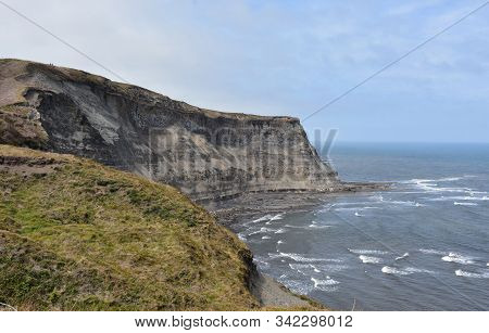 Towering Eroding Sand Sea Cliffs Above A Bay In England.