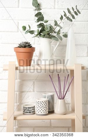 Beautiful Plants And Accessories On Shelves Near Brick Wall At Home