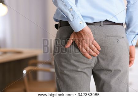 Man Suffering From Hemorrhoid In Office, Closeup