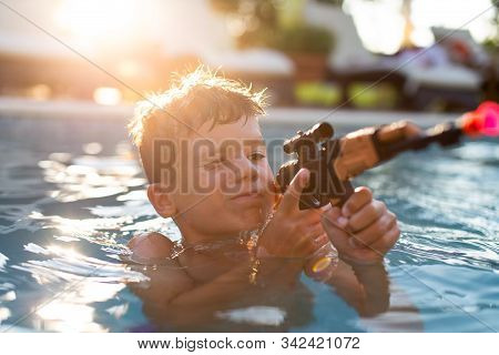 Little Boy Targeting With Suction Cup Gun Toy In Swimming Pool, Summer Holiday