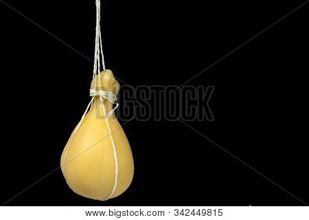 Typical Italian Cheese Caciocavallo Ripens In Ropes. On A Dark Background.