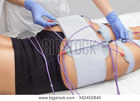 The Procedure Of Myostimulation On The Legs And Buttocks Of A Woman In A Beauty Salon. Overweight Tr