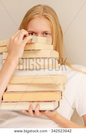 Teenage Girl Hiding Behind Big Pile Of Books She Wants To Read. Student Ready To Study Concept