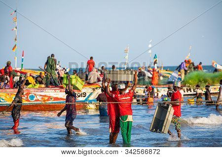 Tanji, The Gambia - November 21, 2019: Scene With Men And Women Carrying Fish From The Boats To The