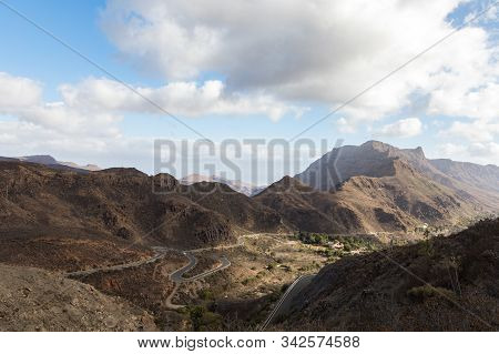 Curved Winding Road With A Red Car In The Mountains In Gran Canaria